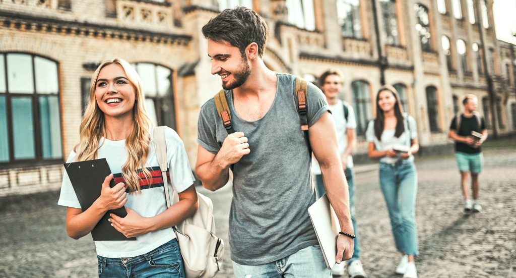 Start ins Studium - Eine Gruppe Freunde laufen gemeinsam vor ihrer Universität