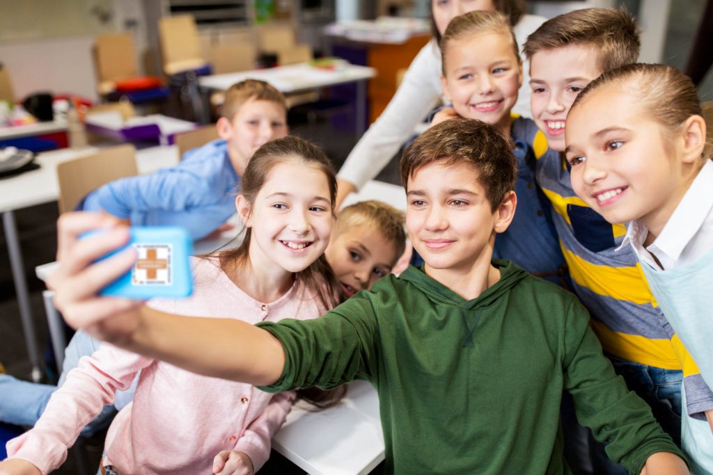 Aktion zum Wechsel - Junge macht mit seinen Freunden ein Selfie in der Schule